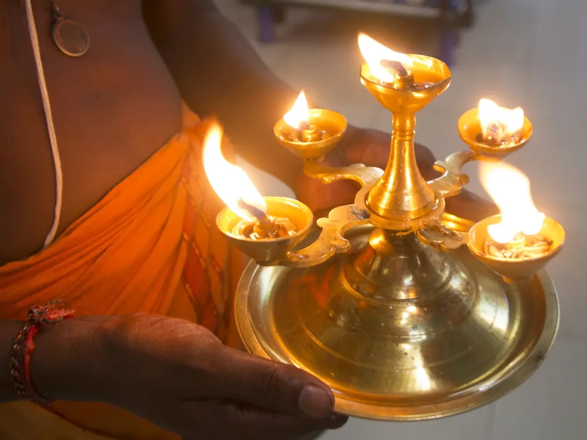 Lampe à huile à plusieurs mèches tenue à deux mains lors d'une cérémonie d'aarti