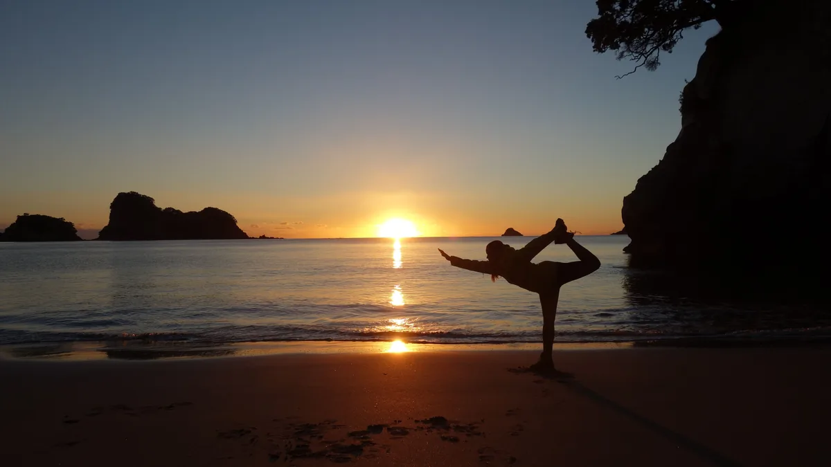 Silhouette en posture de l'arbre sur une plage au coucher du soleil dans une baie rocheuse de Thaïlande